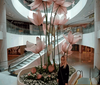 Tall pink floral art installation in the center of a stylish shopping mall.